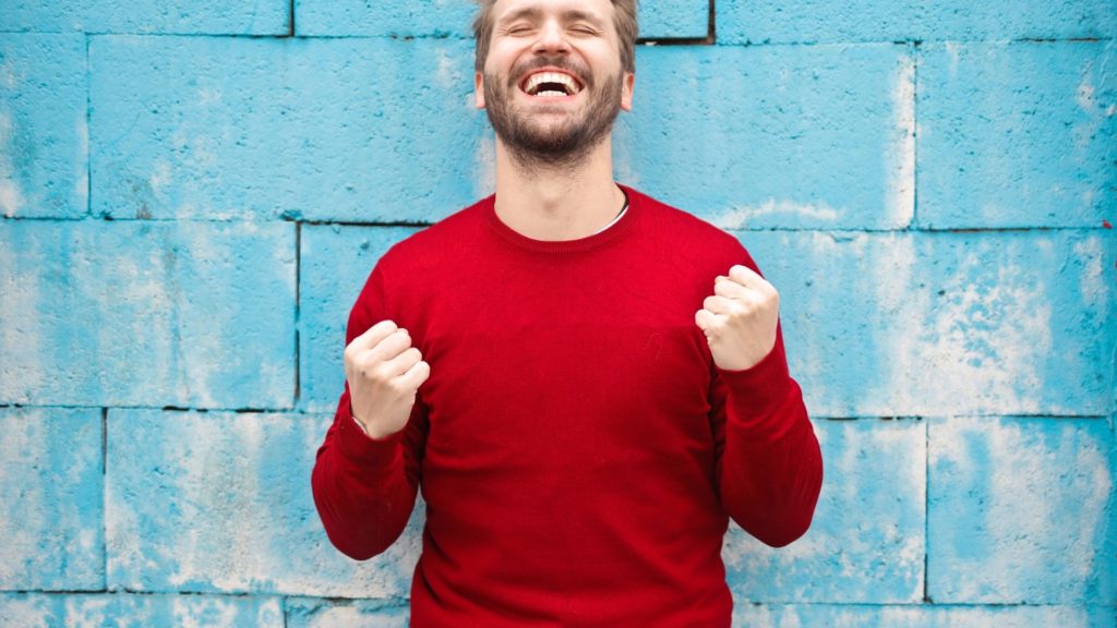 un hombre sonriendo y con los brazos indicando que ha conseguido algo